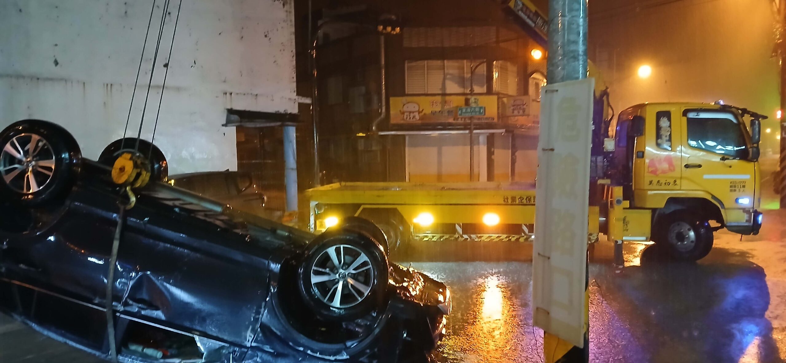 夜間雨中事故車輛拖吊作業示意，道路救援人員進行車輛排除作業